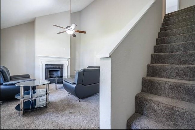 interior space with stairway, a ceiling fan, carpet floors, a fireplace, and vaulted ceiling