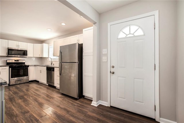 kitchen featuring dark hardwood / wood-style flooring, tasteful backsplash, stainless steel appliances, sink, and white cabinetry