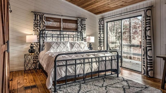 bedroom with visible vents, wooden walls, wood ceiling, and hardwood / wood-style flooring