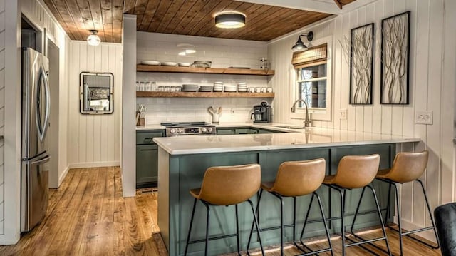 bar with a sink, wood finished floors, appliances with stainless steel finishes, and wooden ceiling