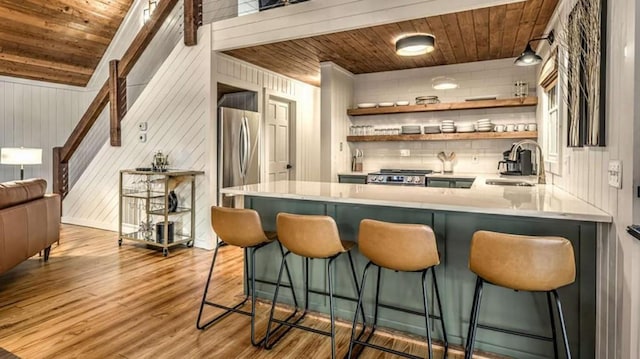 bar featuring wooden ceiling, wood finished floors, freestanding refrigerator, and a sink