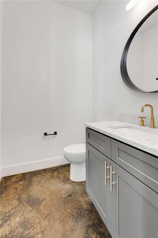 bathroom featuring baseboards, toilet, unfinished concrete floors, and vanity