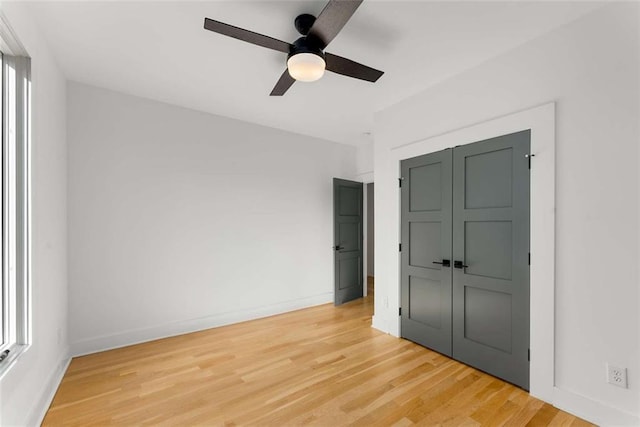 unfurnished bedroom with a closet, baseboards, light wood-style floors, and ceiling fan