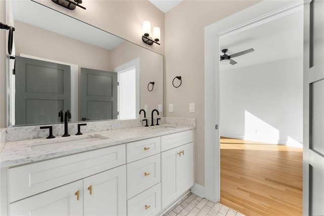 bathroom with a sink, double vanity, wood finished floors, and a ceiling fan