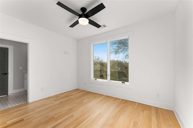 spare room featuring wood finished floors, visible vents, and baseboards