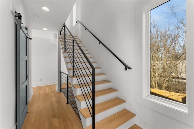 staircase featuring recessed lighting, a barn door, and wood finished floors