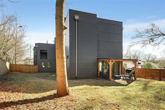 rear view of property featuring a yard and a fenced backyard