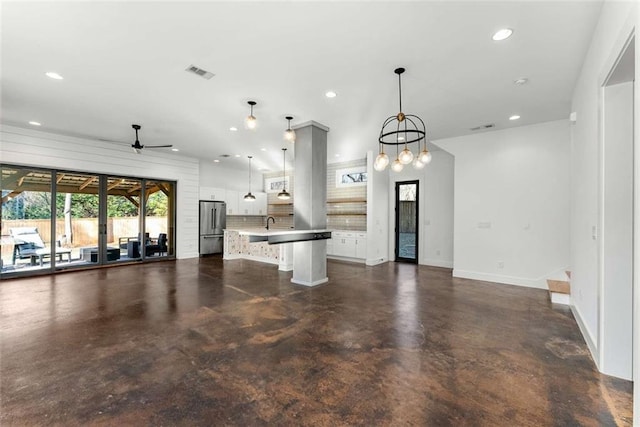 kitchen with open floor plan, white cabinetry, recessed lighting, freestanding refrigerator, and concrete flooring