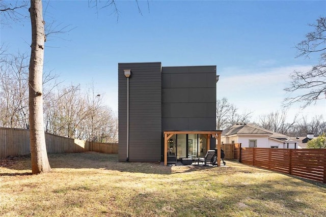 rear view of property featuring a fenced backyard, a yard, and a patio area