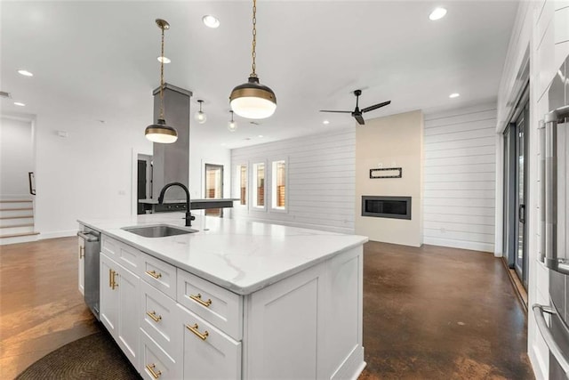 kitchen featuring white cabinetry, concrete floors, a sink, a glass covered fireplace, and open floor plan