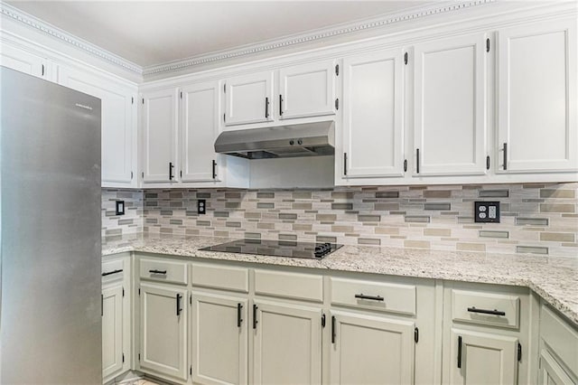 3003 Hanover Ln SE, Conyers, GA 30094 - kitchen with freestanding refrigerator, under cabinet range hood, black electric cooktop, backsplash, and light stone counters