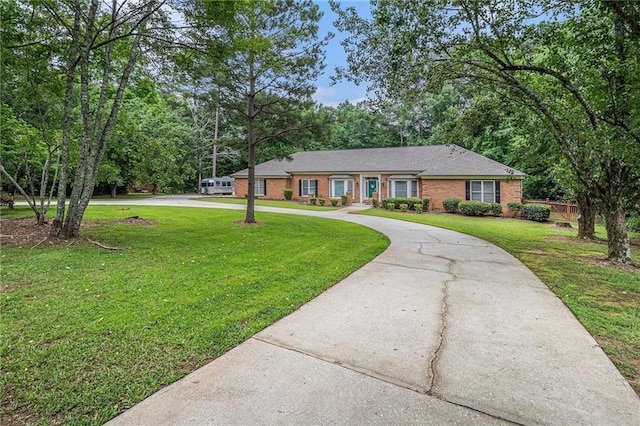 3003 Hanover Ln SE, Conyers, GA 30094 - ranch-style house with curved driveway, a front lawn, brick siding, and view of scattered trees