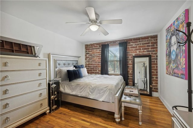 bedroom featuring brick wall, wood finished floors, a ceiling fan, and baseboards