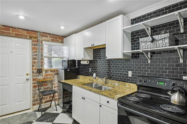 kitchen with white cabinets, light stone counters, black appliances, open shelves, and a sink