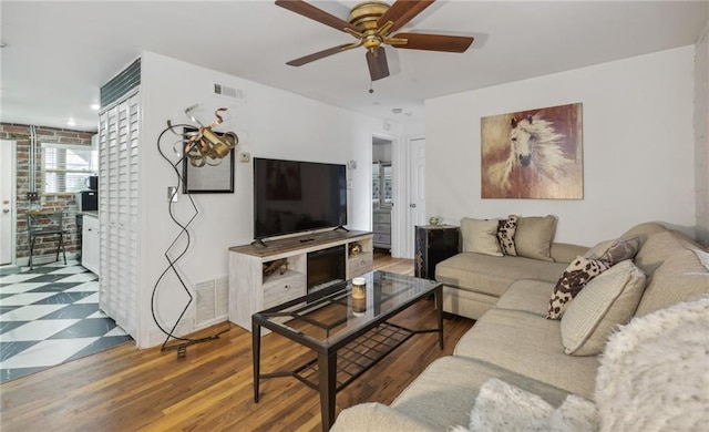 living area with a ceiling fan, visible vents, and wood finished floors