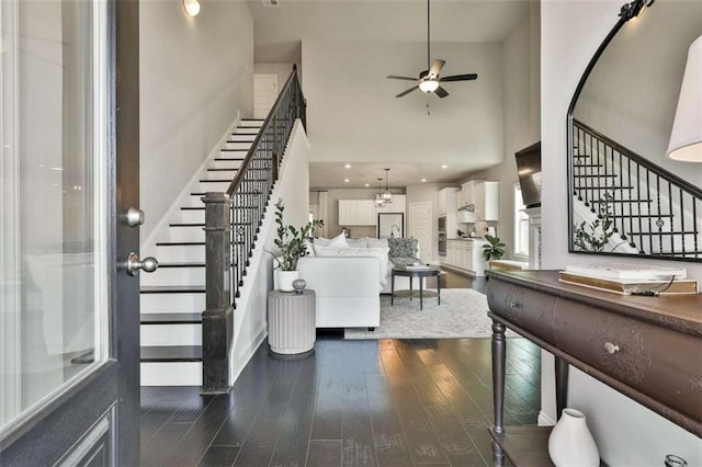 entryway featuring a high ceiling, ceiling fan with notable chandelier, and dark hardwood / wood-style flooring