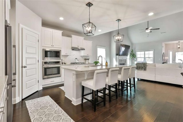 kitchen featuring white cabinetry, stainless steel appliances, a kitchen island with sink, and pendant lighting