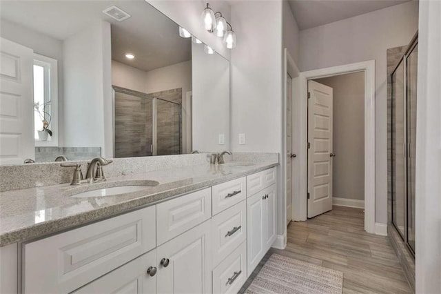 bathroom with vanity, an enclosed shower, and wood-type flooring