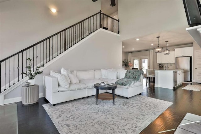 living room featuring dark wood-type flooring, sink, and an inviting chandelier