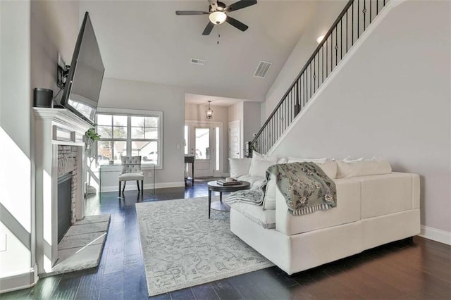 living room with dark hardwood / wood-style flooring, a brick fireplace, lofted ceiling, and ceiling fan