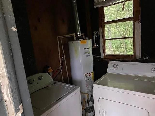 washroom with gas water heater, washer and clothes dryer, and a wealth of natural light