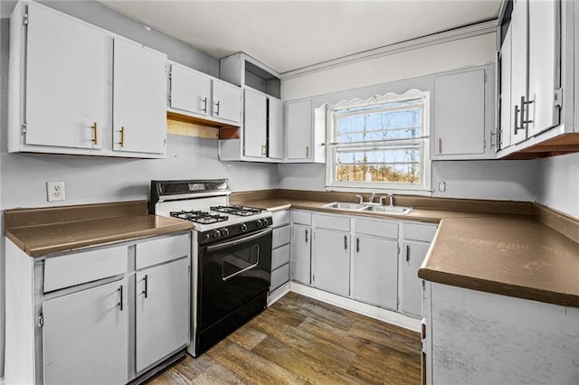 kitchen featuring range with gas cooktop, white cabinetry, sink, crown molding, and dark wood-type flooring