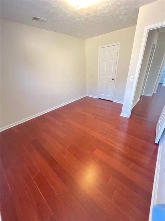 empty room featuring a textured ceiling and hardwood / wood-style flooring