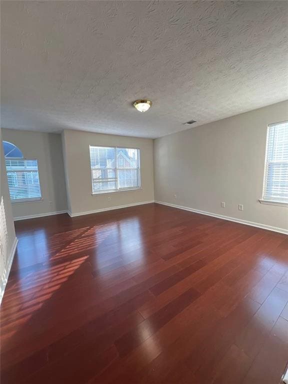 empty room with a textured ceiling and dark wood-type flooring