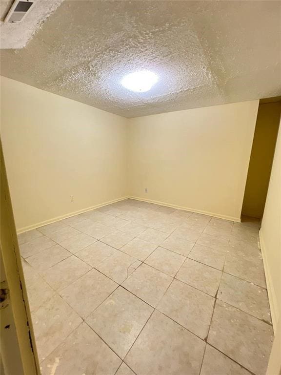 empty room featuring light tile patterned floors and a textured ceiling