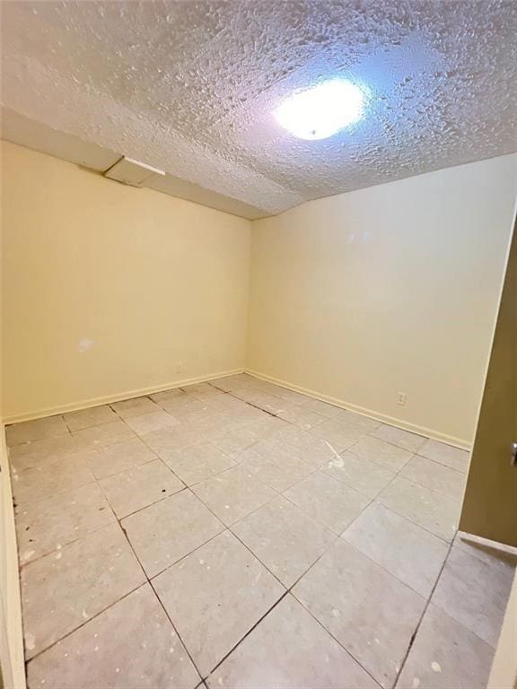 tiled empty room with a textured ceiling