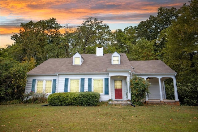 cape cod-style house featuring a lawn