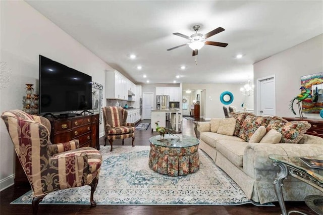 living room with dark hardwood / wood-style flooring and ceiling fan with notable chandelier