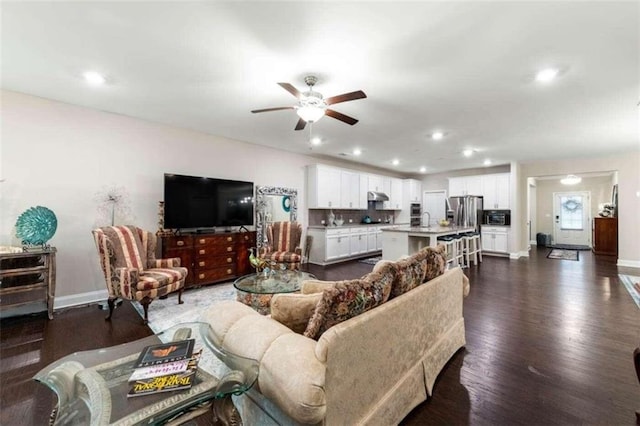 living room featuring ceiling fan, dark hardwood / wood-style floors, and sink