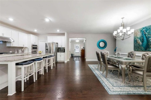 dining room featuring a notable chandelier, sink, and dark hardwood / wood-style floors