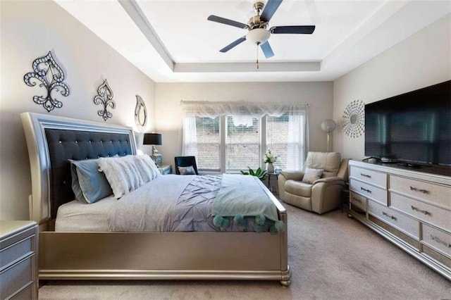 carpeted bedroom featuring ceiling fan and a tray ceiling