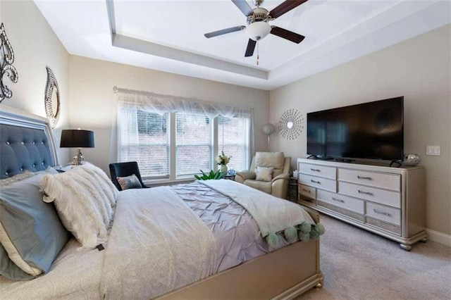 bedroom featuring light carpet, ceiling fan, and a raised ceiling