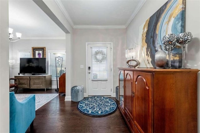 entrance foyer featuring dark hardwood / wood-style flooring, ornamental molding, and an inviting chandelier