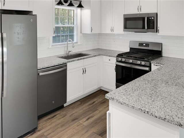 kitchen with dark wood-type flooring, sink, white cabinets, appliances with stainless steel finishes, and light stone countertops