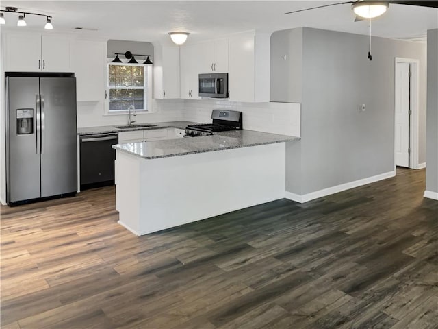 kitchen with light stone counters, sink, white cabinets, kitchen peninsula, and appliances with stainless steel finishes