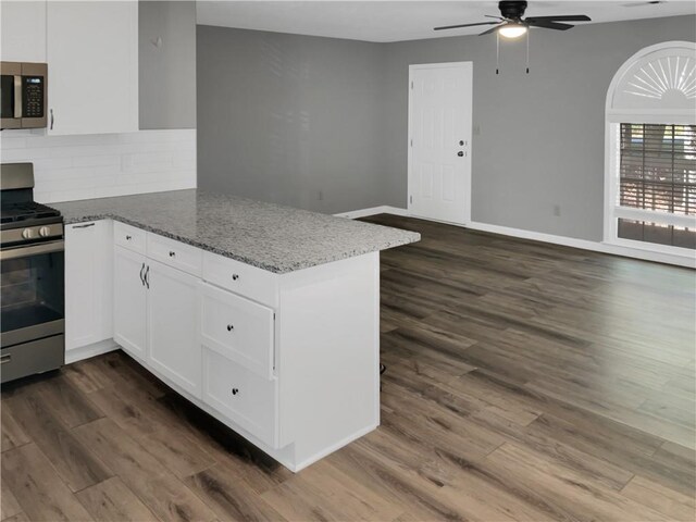 kitchen with appliances with stainless steel finishes, white cabinetry, kitchen peninsula, dark hardwood / wood-style flooring, and ceiling fan