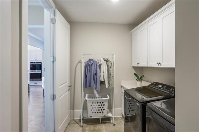 clothes washing area featuring cabinet space, baseboards, and washing machine and dryer