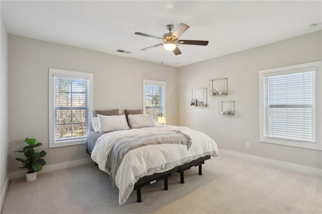 carpeted bedroom with visible vents, baseboards, ceiling fan, and multiple windows