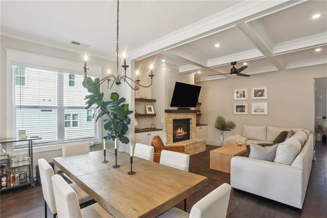dining area featuring ceiling fan with notable chandelier, a brick fireplace, dark wood-style floors, and visible vents