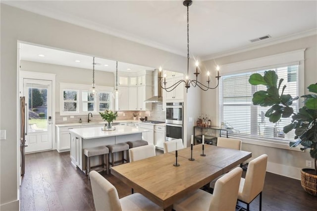 dining room featuring crown molding, visible vents, a notable chandelier, and dark wood-type flooring