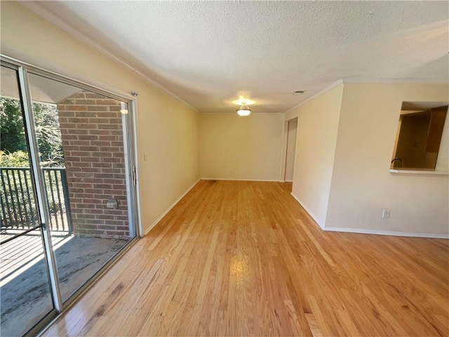 spare room with a textured ceiling and light hardwood / wood-style flooring