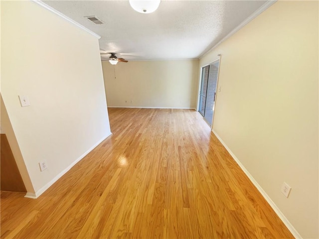 empty room featuring ceiling fan, light wood-type flooring, and crown molding