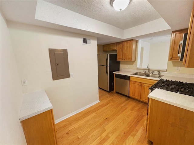 kitchen featuring a textured ceiling, stainless steel appliances, sink, light hardwood / wood-style flooring, and electric panel