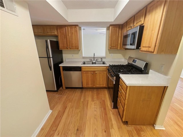 kitchen with sink, stainless steel appliances, and light hardwood / wood-style floors