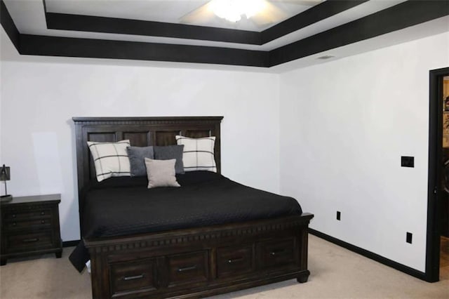 bedroom featuring a raised ceiling and light carpet