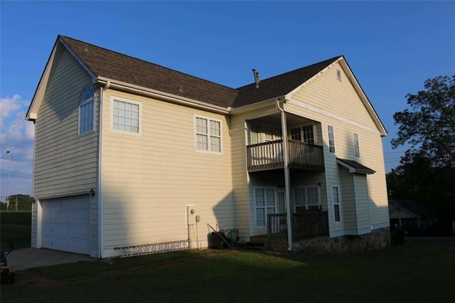 rear view of house featuring a garage and a balcony